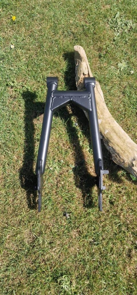 Top view of a motorcycle swing arm in Cerakote Graphite Black H-146 showing welds and pivot
